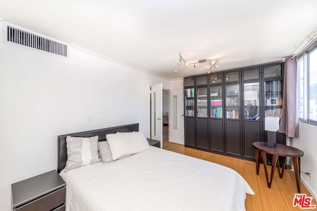 bedroom featuring crown molding and light wood-type flooring