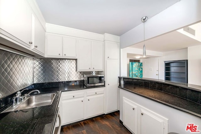 kitchen with white cabinetry, dark stone countertops, hanging light fixtures, and dark hardwood / wood-style flooring