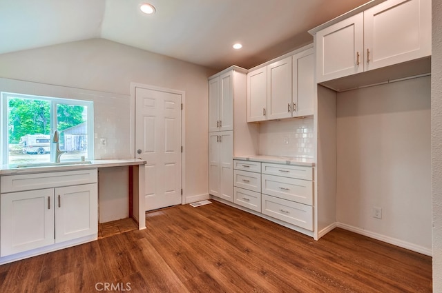 kitchen with sink, white cabinetry, lofted ceiling, dark wood-type flooring, and decorative backsplash