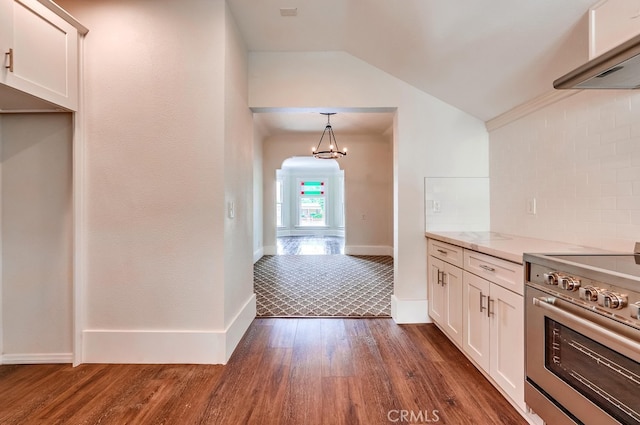 kitchen with lofted ceiling, white cabinetry, stainless steel stove, dark wood-type flooring, and decorative light fixtures