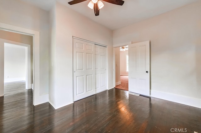 unfurnished bedroom featuring dark wood-type flooring, a closet, and ceiling fan