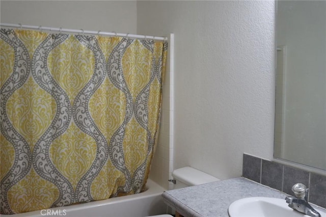 full bath featuring decorative backsplash, vanity, shower / bathtub combination with curtain, a textured wall, and toilet