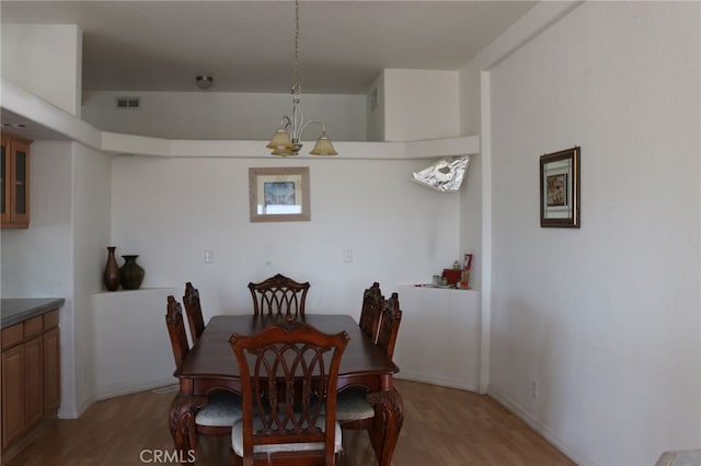 dining space with light hardwood / wood-style flooring and a chandelier