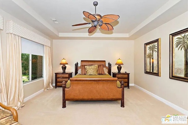 carpeted bedroom with ceiling fan and a raised ceiling