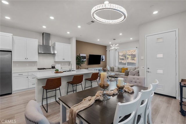 dining area featuring sink, a chandelier, and light hardwood / wood-style flooring