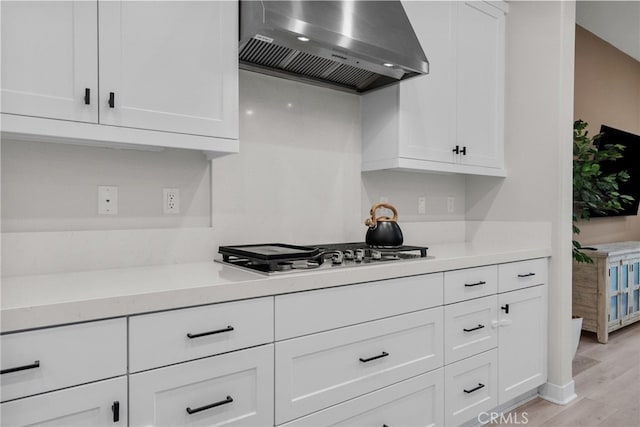 kitchen with wall chimney exhaust hood, light wood-type flooring, and white cabinetry