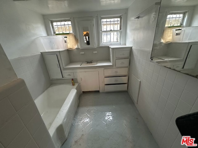 bathroom with a tub, tile walls, and sink