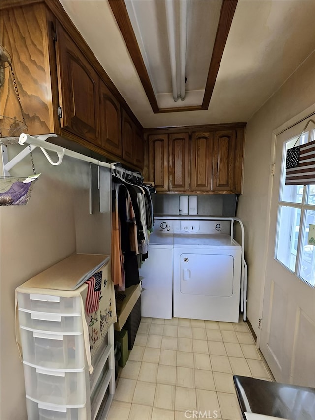 clothes washing area featuring cabinets and washer and clothes dryer