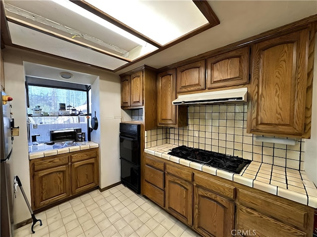 kitchen with double oven, decorative backsplash, tile counters, and gas stovetop