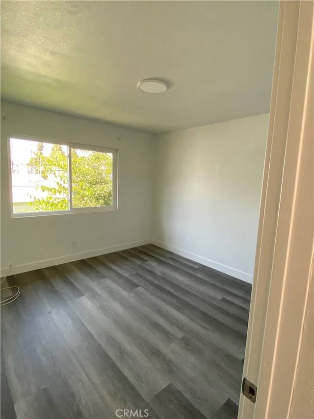 spare room with a textured ceiling and dark wood-type flooring