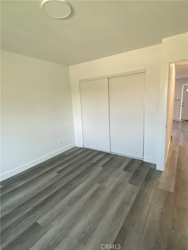 unfurnished bedroom with dark hardwood / wood-style floors and a closet