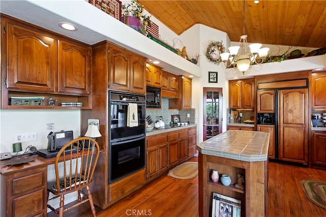 kitchen with black appliances, vaulted ceiling, tile counters, dark wood-type flooring, and an inviting chandelier