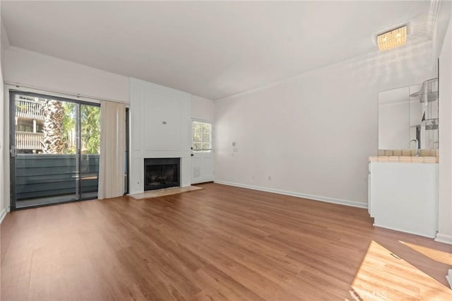 unfurnished living room featuring sink, a healthy amount of sunlight, and wood-type flooring