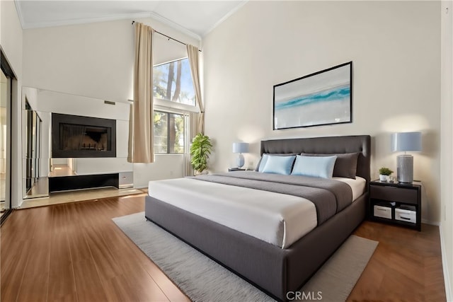 bedroom featuring hardwood / wood-style floors, crown molding, and high vaulted ceiling