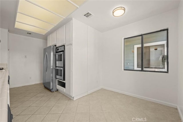 kitchen with white cabinetry, stainless steel appliances, and light tile patterned floors