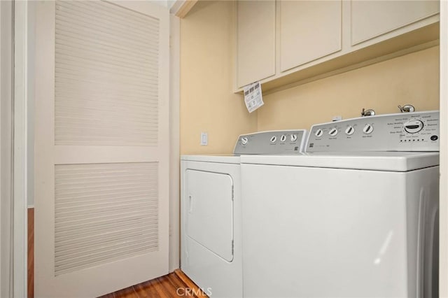 laundry area with washer and clothes dryer, dark hardwood / wood-style floors, and cabinets