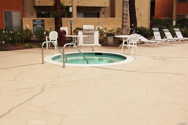 view of swimming pool with grilling area, a community hot tub, and a patio