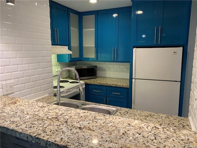 kitchen featuring blue cabinetry, light stone counters, tasteful backsplash, and white appliances