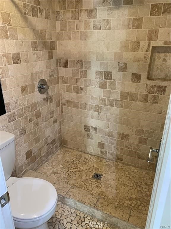 bathroom with tiled shower and toilet