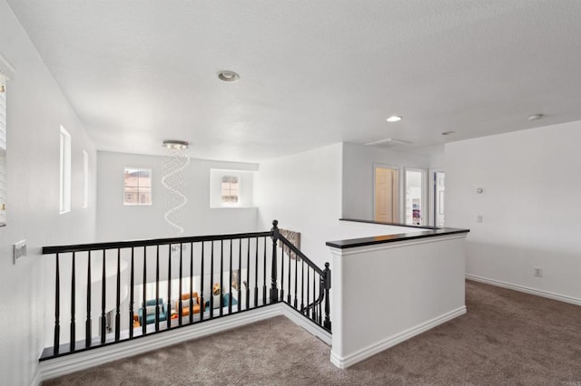 hallway featuring a notable chandelier and carpet floors