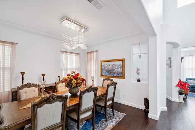 dining room featuring a notable chandelier, dark wood-type flooring, and a wealth of natural light