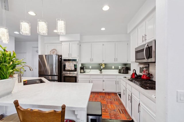 kitchen with hanging light fixtures, sink, a breakfast bar, white cabinetry, and appliances with stainless steel finishes