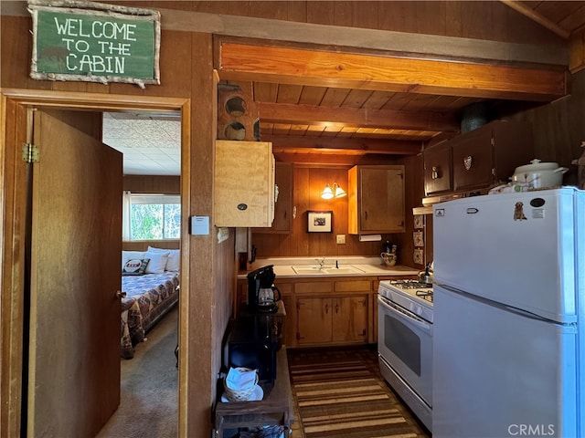 kitchen featuring beamed ceiling, wooden walls, white appliances, dark carpet, and tile countertops