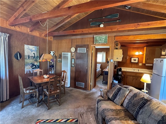 carpeted living room with vaulted ceiling with beams, sink, wooden ceiling, and wooden walls