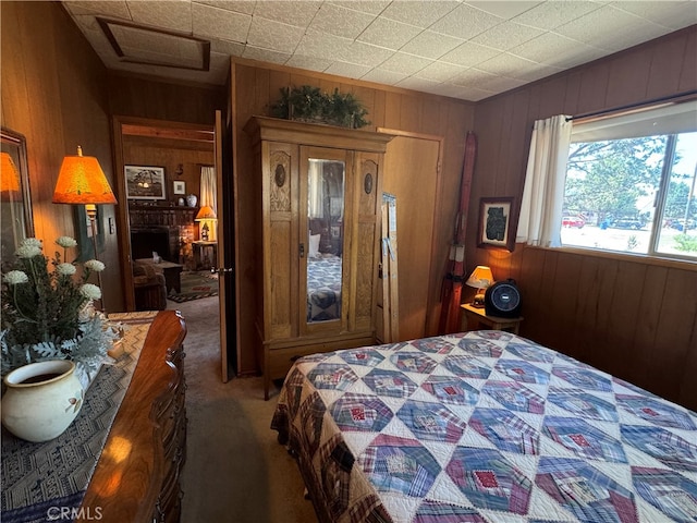 bedroom with a fireplace, wood walls, and carpet