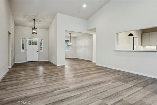 entryway featuring a towering ceiling and light wood-type flooring