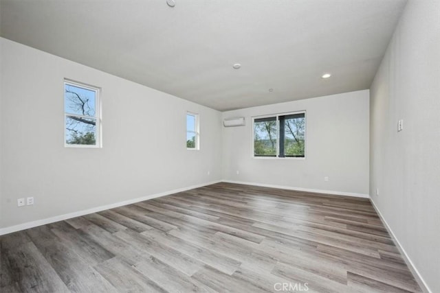 spare room with light hardwood / wood-style floors and a wall mounted air conditioner