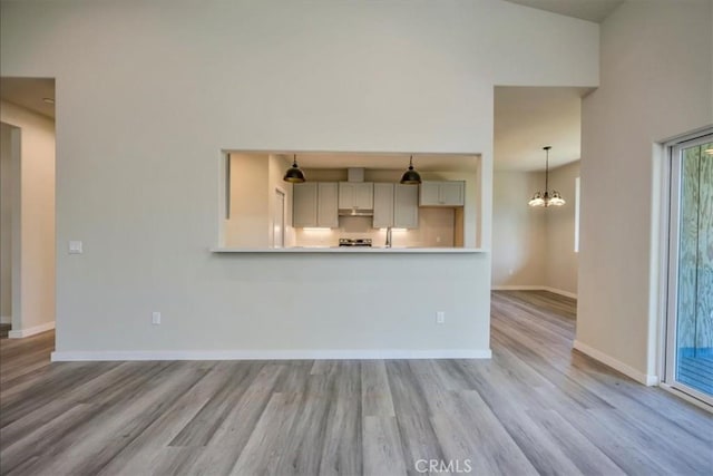 unfurnished living room with light hardwood / wood-style floors, a chandelier, and vaulted ceiling