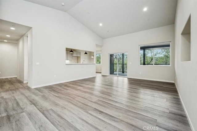 unfurnished living room featuring light hardwood / wood-style flooring and high vaulted ceiling