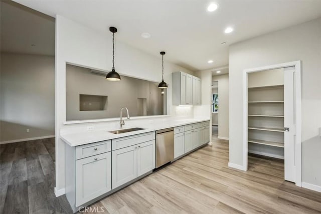 kitchen featuring light hardwood / wood-style floors, stainless steel dishwasher, pendant lighting, and sink