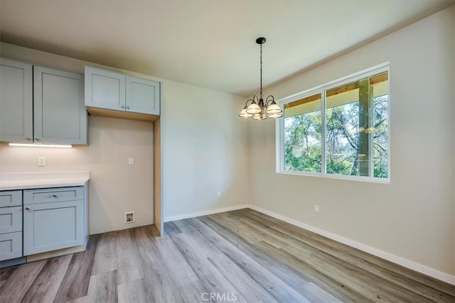 kitchen featuring pendant lighting, an inviting chandelier, and light hardwood / wood-style floors