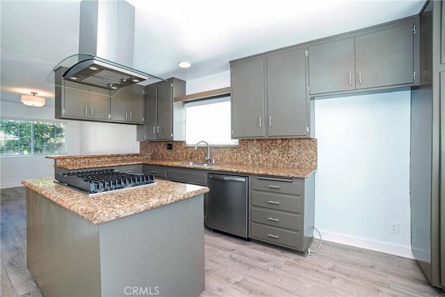 kitchen with appliances with stainless steel finishes, island range hood, gray cabinets, and a wealth of natural light