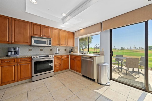 kitchen featuring decorative backsplash, stainless steel appliances, a raised ceiling, sink, and light tile patterned flooring