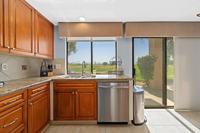 kitchen featuring tasteful backsplash, sink, light stone counters, stainless steel dishwasher, and light tile patterned floors