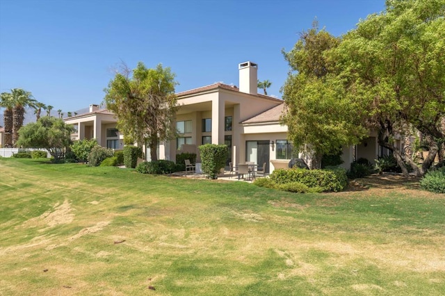 rear view of house featuring a lawn and a patio