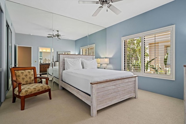 carpeted bedroom with ensuite bathroom and ceiling fan