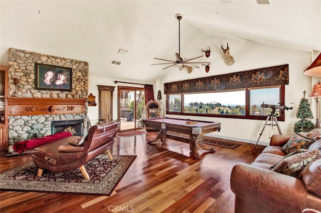 living room with vaulted ceiling, billiards, a stone fireplace, wood-type flooring, and ceiling fan