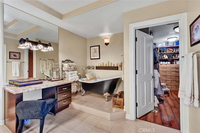 bathroom with a raised ceiling, vanity, a tub, and hardwood / wood-style flooring