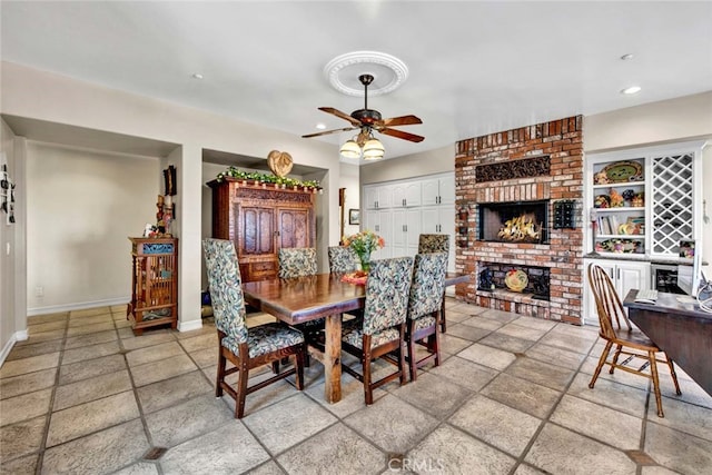 dining space featuring a brick fireplace and ceiling fan