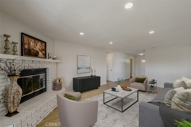 living room featuring a brick fireplace and light wood-type flooring