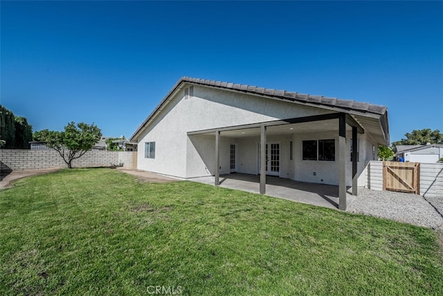 rear view of property featuring a patio area and a lawn