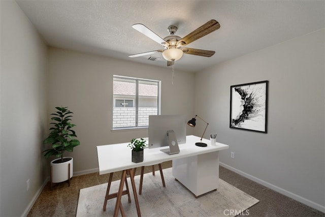 carpeted home office featuring a textured ceiling and ceiling fan