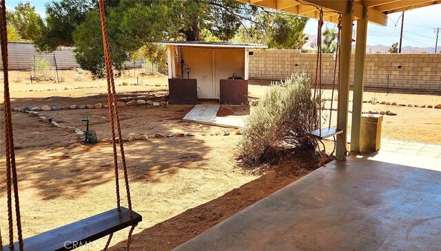 view of patio / terrace with an outbuilding, fence, and a shed