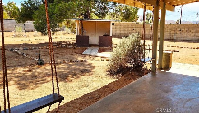 view of patio featuring an outdoor structure, a storage unit, and fence