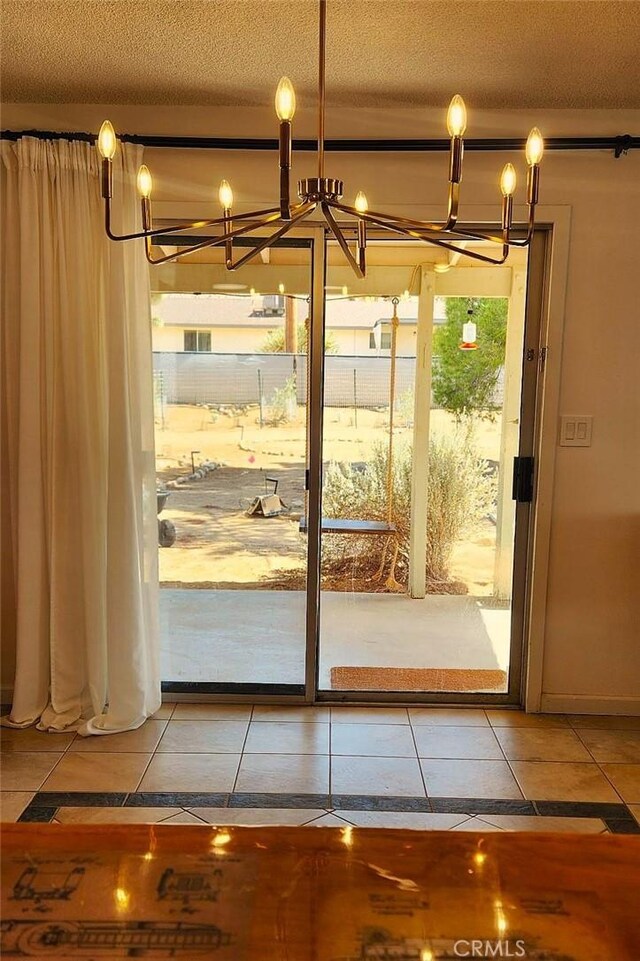 doorway to outside with a notable chandelier, tile patterned flooring, and a textured ceiling