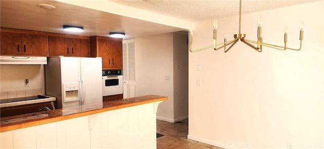 kitchen featuring light tile patterned floors, decorative light fixtures, white appliances, and ventilation hood